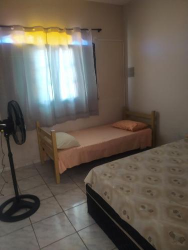 a small bedroom with two beds and a window at Casa com piscina Mongaguá 2 quartos in Mongaguá