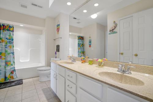a bathroom with two sinks and a toilet and a mirror at Charlie's Bayside Retreat - Pet friendly, In town! in Chincoteague