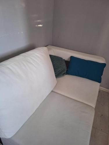 a white couch with two blue pillows on it at Au Cœur De Chateaubriant WIFI-Centre-Ville-RDC in Châteaubriant