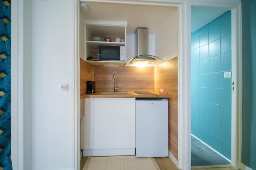 une petite cuisine avec un évier et un réfrigérateur dans l'établissement L'Atelier Lobau Nancy - Studio Élégant en Centre-Ville, à Nancy
