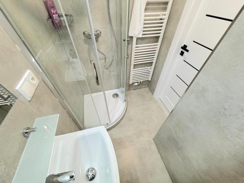 La salle de bains est pourvue d'une douche et d'un lavabo blanc. dans l'établissement Krásny byt - apartmán 7 v blízkosti centra, à Bratislava