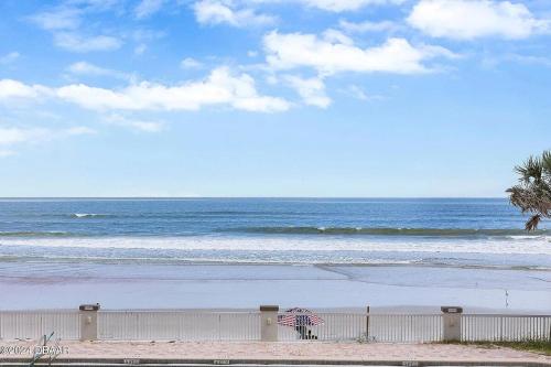 ein Strand mit einem Sonnenschirm und dem Meer in der Unterkunft Amazing Ocean View Beachfront Entire Apartment Direct access to Beach in Daytona Beach