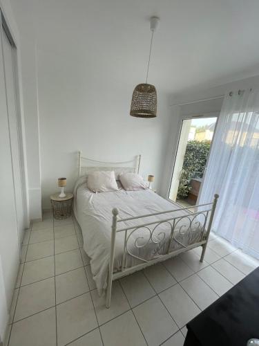 un lit blanc dans une chambre blanche avec une fenêtre dans l'établissement APT CHATELAILLON - 6 people -PLAGE CASINO, à Châtelaillon-Plage