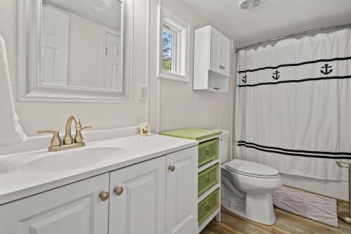 un bagno bianco con lavandino e WC di Counting Corks - Waterfront, Pet friendly, private dock! a Eastville