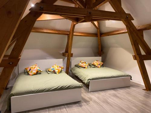 two beds in a attic room with wooden beams at La porte du jardin in Saint-Aubin-de-Nabirat