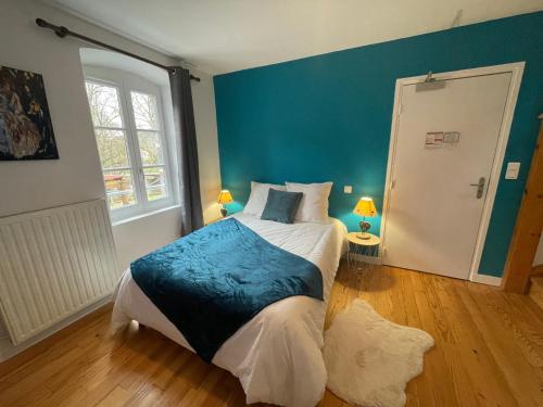 a bedroom with a large bed with a blue wall at Le Matagot Auberge-Restaurant in Mazeyrat-Aurouze