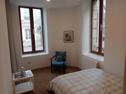 a bedroom with a bed and a chair and windows at Sasha in Brive-la-Gaillarde