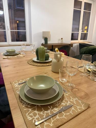 - une table en bois avec un bol vert et des assiettes dans l'établissement L'appart d'Arches - 85m2 2 chambres centre ville, à Charleville-Mézières