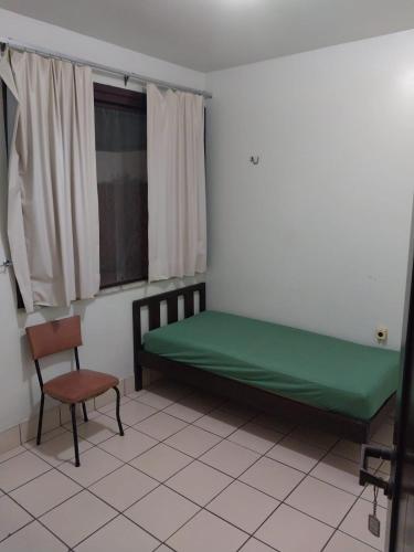 a bedroom with a green bed and a chair at Casa Merlini - Hotel e salas Comerciais in Belém