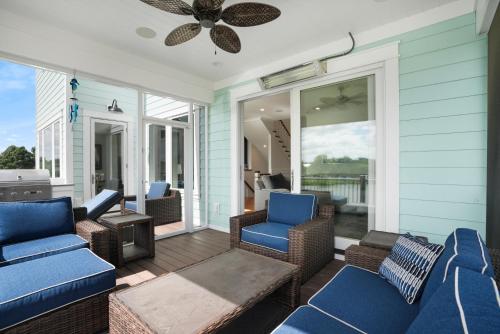 a porch with chairs and a couch and a table at Day Dream Believer - New Construction, Upscale Resort, Many Amenities! in Cape Charles