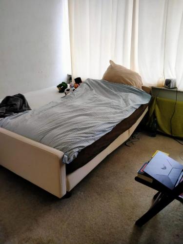 an unmade bed in a bedroom next to a window at De Deken in Best