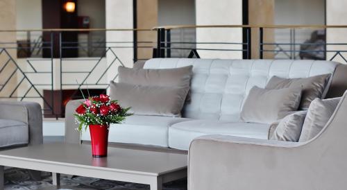 a white couch and a table with a vase of flowers at Grand Mogador City Center in Casablanca
