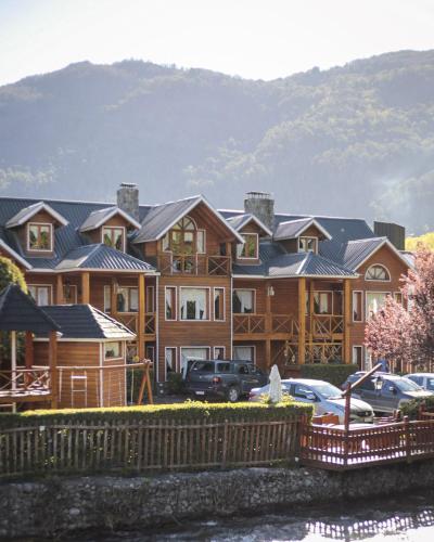 a large house with cars parked in front of it at Apart Presidencial ROTUI in San Martín de los Andes