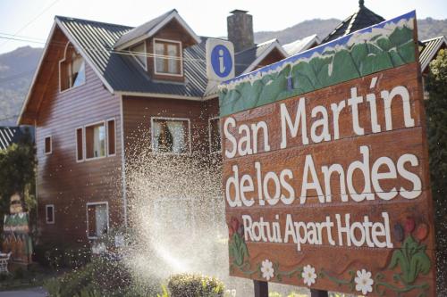a sign in front of a house with a building at Apart Presidencial ROTUI in San Martín de los Andes