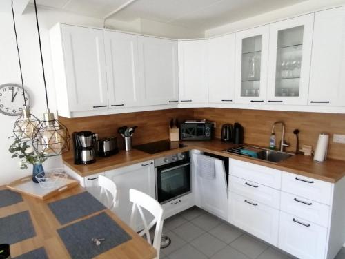 a white kitchen with white cabinets and a table at Ferienhaus 2004 in Tossens in Tossenserdeich