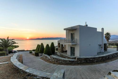 a white house with a sunset in the background at Villa Kalí Méra in Aëtós