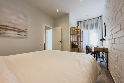 a bedroom with a white bed and a desk at Novus Homes Barcelona Santa Eulalia in Hospitalet de Llobregat