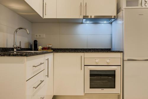 a kitchen with white cabinets and a sink at Novus Homes Barcelona Santa Eulalia in Hospitalet de Llobregat