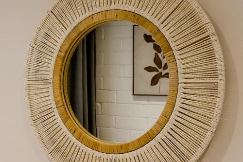 a rattan mirror with a wicker frame on a wall at Novus Homes Barcelona Santa Eulalia in Hospitalet de Llobregat
