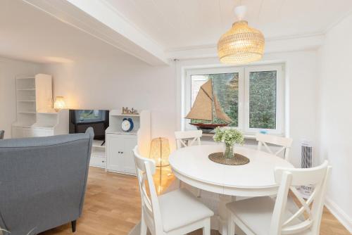 a dining room with a white table and chairs at Deich-Ferienhaus 65 qm Königsberger Allee 38 APPARTO Grömitz in Grömitz