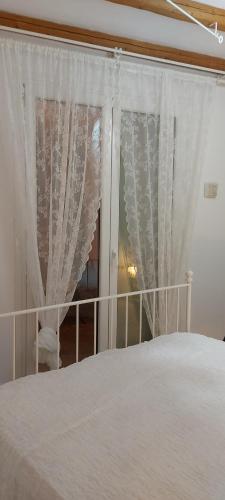 a bedroom with a bed with white curtains at Aegean Breeze in DYO CHORIA TINOS in Triandáros