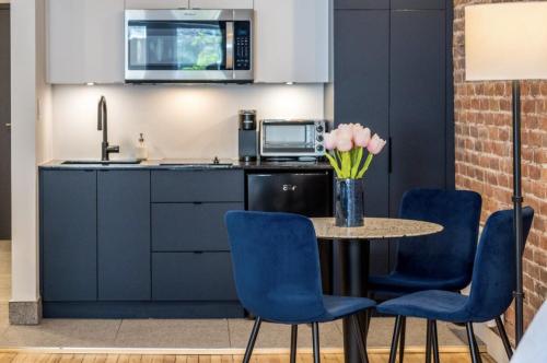 une cuisine avec des chaises bleues et une table avec un vase de fleurs dans l'établissement Initial / Suite trésor / Centre-Ville de Québec, à Québec