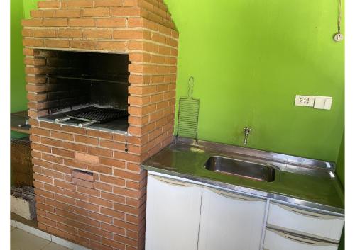 a kitchen with a brick fireplace and a sink at Cantinho da Cerejeira in Santo Antônio do Pinhal