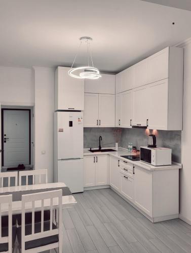 a kitchen with white cabinets and a white refrigerator at Apartments in Comfort city 142, Almaty in Almaty