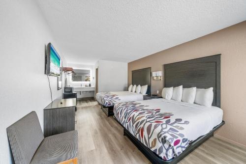 a hotel room with two beds and a desk at Executive Inn - Panama City Beach in Panama City Beach