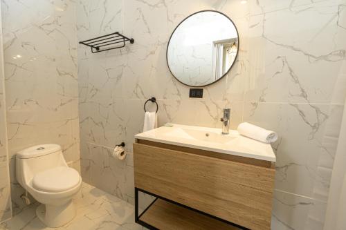 a bathroom with a toilet and a sink and a mirror at Soleil Suites in Iquitos