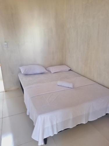 a bed in a room with white sheets and pillows at Quarto duplo ventilador in Conde