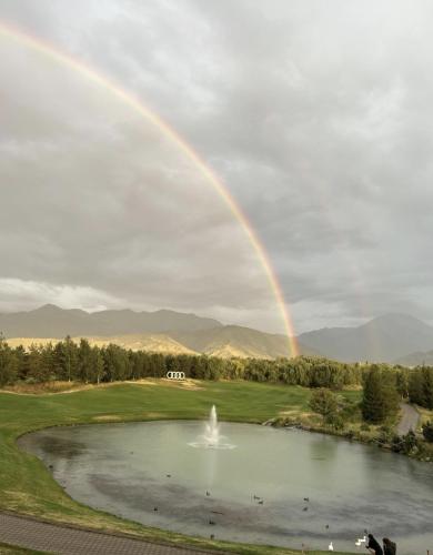 a rainbow over a pond with a fountain at Apartments in Comfort city 142, Almaty in Almaty