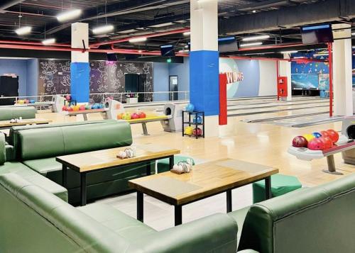 a restaurant with green chairs and tables and bowling lanes at Apartments in Comfort city 142, Almaty in Almaty