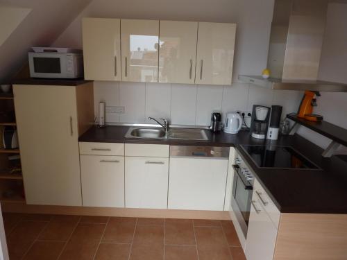 a small kitchen with white cabinets and a sink at Ostseebrise 14 - Großenbrode in Grossenbrode