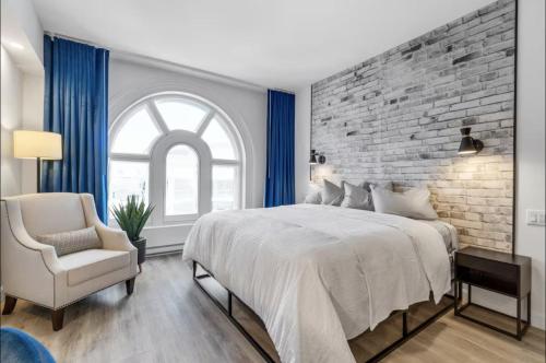 a bedroom with a large bed and a brick wall at INITIAL - SUITE JOCONDE - Centre-Ville de Québec in Quebec City