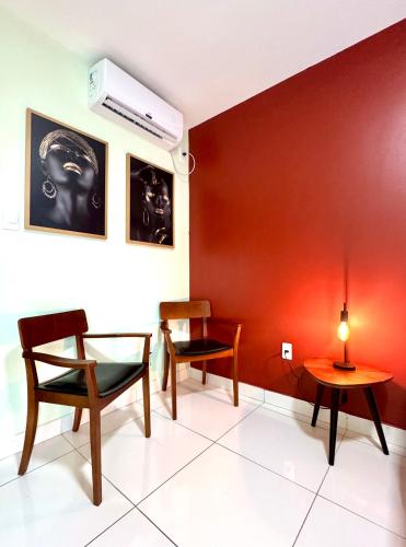 a room with two chairs and a red wall at Studio Charmoso e Aconchegante em Itaberaba II in Itaberaba
