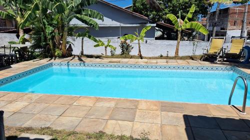 a swimming pool with blue water in a yard at Guest House Flor de Laranjeira in São Pedro da Aldeia