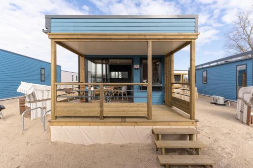 a tiny house with a deck on the beach at Boje 73 in Scharbeutz