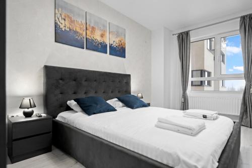 a bedroom with a large white bed with blue pillows at Minimalist Green & Grey Flat in Bucharest