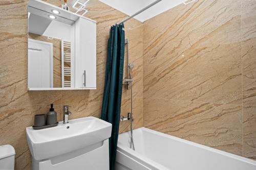 a bathroom with a sink and a tub and a mirror at Minimalist Green & Grey Flat in Bucharest