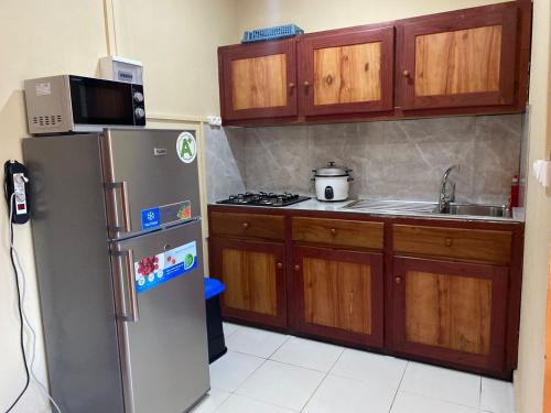 a kitchen with a stainless steel refrigerator and wooden cabinets at Residence Kathyly in Diego Suarez