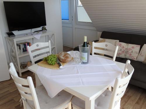 a white table with a plate of food and a tv at Haus Wildfang FeWo 2 in Dahme