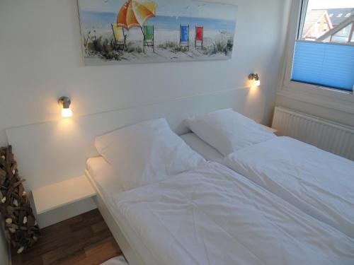 a white bed in a bedroom with a picture on the wall at Haus Wildfang FeWo 2 in Dahme