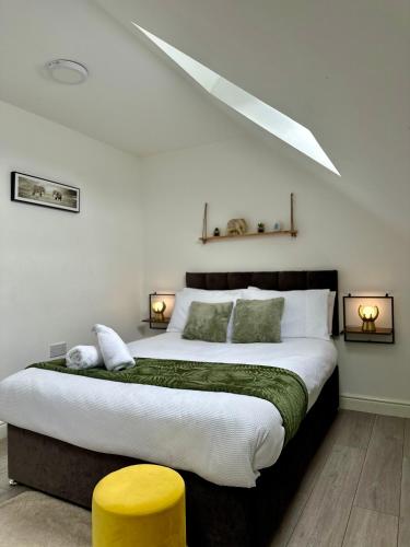 a bedroom with a large bed with a yellow stool at Cosy 3 Bed Apartment Near Birmingham Airport & NEC Perfect for Groups & Contractors! in Birmingham