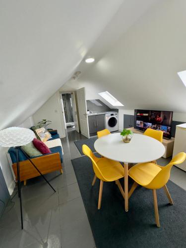 a living room with a table and yellow chairs at Cosy 3 Bed Apartment Near Birmingham Airport & NEC Perfect for Groups & Contractors! in Birmingham