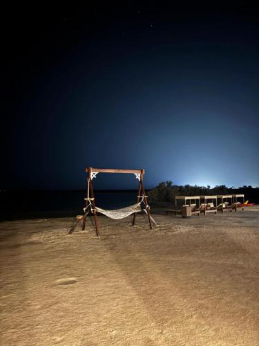 a hammock sitting in the sand on a beach at Mangrove Camp in Sharm El Sheikh