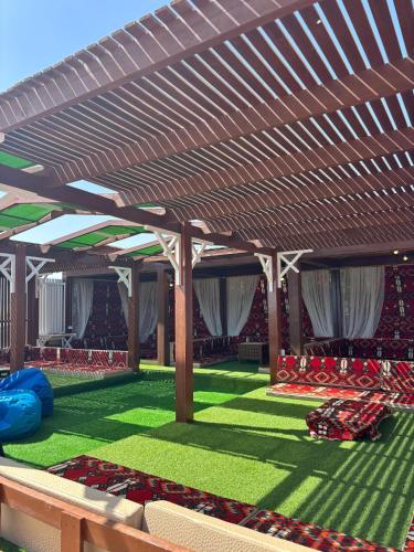 a patio with a wooden pergola and green grass at Mangrove Camp in Sharm El Sheikh