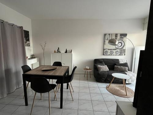 un salon avec une table, des chaises et un canapé dans l'établissement Logement plein centre royan, à Royan