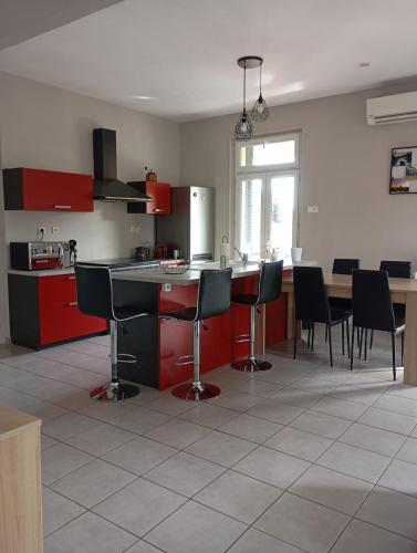 une cuisine avec des armoires rouges et une table et des chaises dans l'établissement Appartement proche des thermes de vals les bains, à Labégude