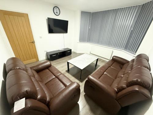 a living room with two leather couches and a tv at Cozy 3 bedroom home in Wyken - Coventry in Wyken